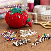 Close-up of a colorful pile of assorted ball head pins with plastic, pearl-style, metallic, and faceted round heads on a white background.